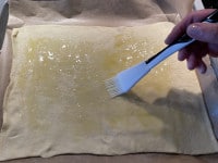 Der Pizza-Teig für die Tarte wird mit Öl bestrichen